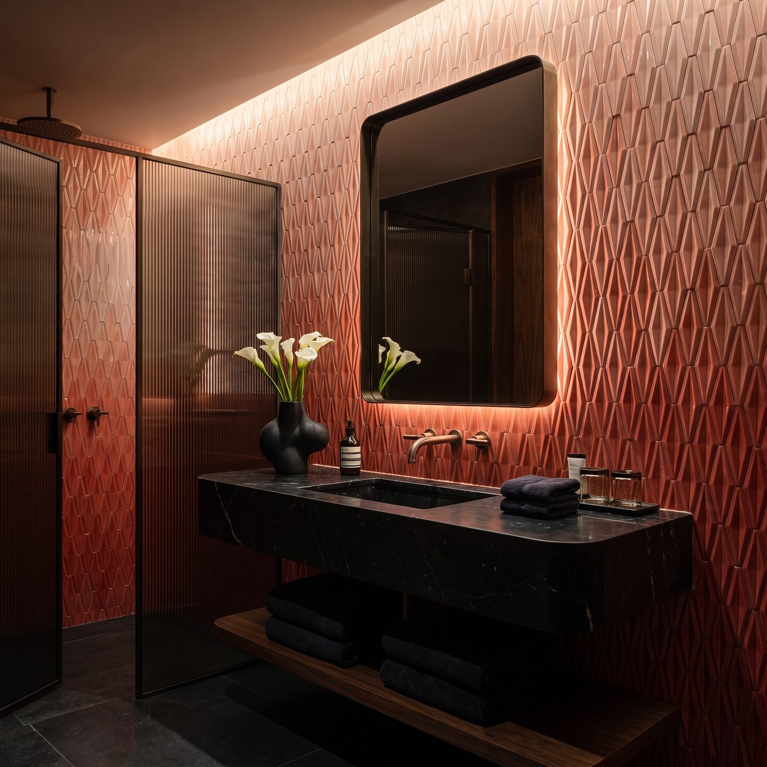 Dark bathroom with a backlit mirror, black stone vanity and a ribbed copper-toned wall.